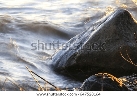 water splashes at rocky shore, golden sunlight