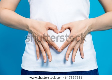 young woman who makes a heart shape by hands on her stomach. Royalty-Free Stock Photo #647537386