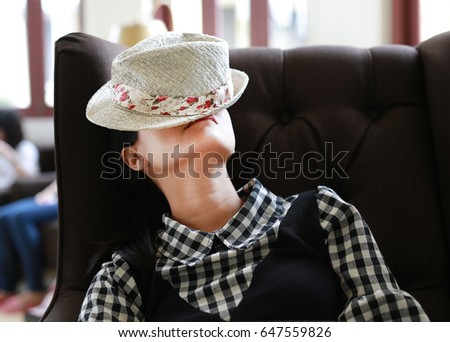 Young asian woman sleeping with hat on face in the library.