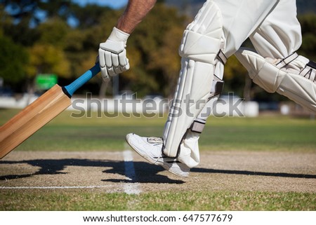 Low section of cricket player scoring run on field during sunny day