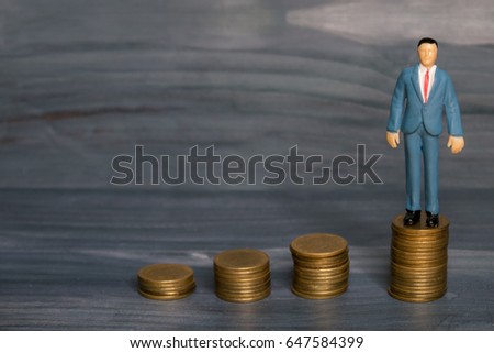 business man stand on stack of coin on gray wooden background in concept successful, saving money, investment