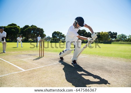 Young man playing cricket at field against clear sky on sunny day