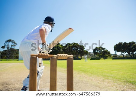 Side view of cricket player batting while playing on field against clear sky Royalty-Free Stock Photo #647586379