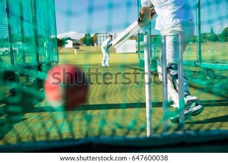 Low section of spoertsman playing cricket at field on sunny day