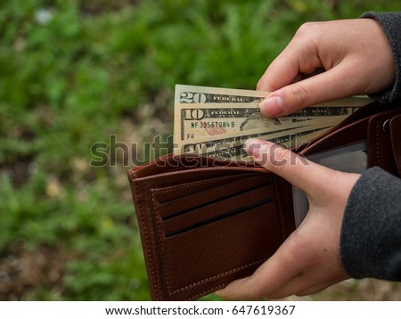 Hands holding us dollar bills and small money pouch. Toned picture