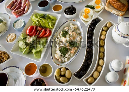 Traditional Turkish Breakfast with salad and olives juice on white table,above view.