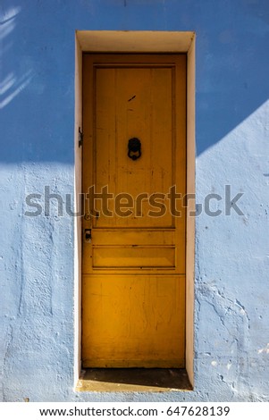 Yellow wooden door at blue wall