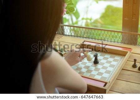 Selective focus closeup toned photo of woman making move with black horse at chess game