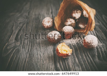 Delicious homemade sour cream ball doughnuts powdered with sugar, on dark wooden background, close up. Toned picture