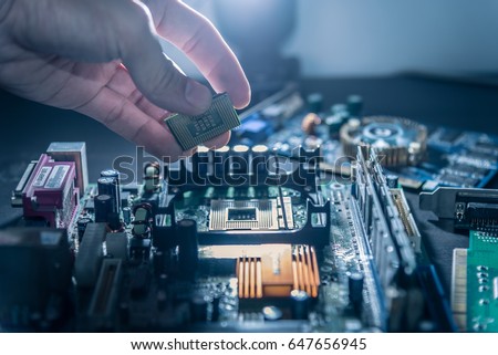 The technician is putting the CPU on the socket of the computer motherboard. Royalty-Free Stock Photo #647656945