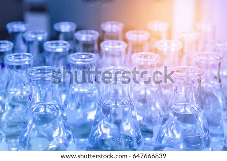 Glass flask with liquid in laboratory. Blue tone. Selective focus.