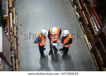 Team of warehouse workers with touchpad making revision of goods Royalty-Free Stock Photo #647680018