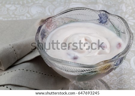 Natural greek yoghurt with berries mixed in lovely glass bowel with napkin - Food background with creamy yoghurt on spoon
