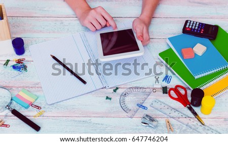 Image of female high school student hand using tablet for studying while writing on the book
