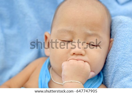 The baby sucks his finger while falling asleep. 
Selective focus. Soft focus.