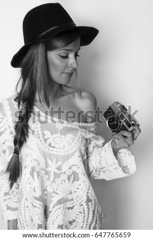 Beautiful girl holding analog camera in hand, black and white, studio shot