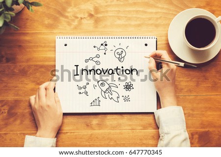 Innovation text with a person holding a pen on a wooden desk