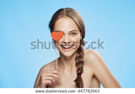 Woman smiling and holding a heart on a stick                               