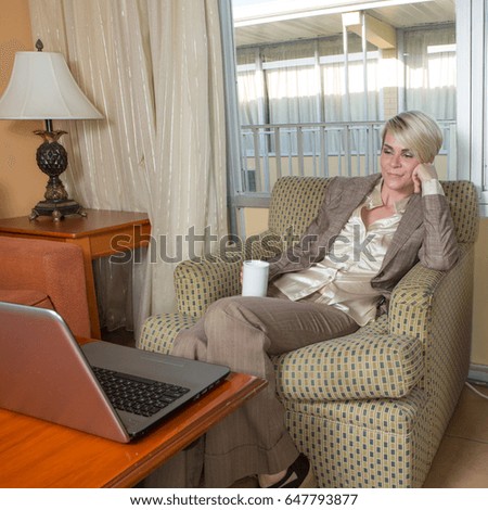 Young blonde businesswoman working in a budget hotel room in a business suite