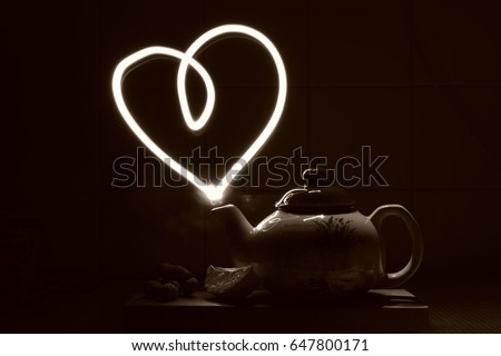 Unusual picture of a teapot created by luminography technique. Heart coming out of the teapot. Light drawing. Love tea. 