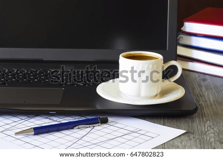 Business concept. Objects on gray background.  Laptop, white cup of coffee, notebooks  and pen. Soft focus.  Horizontal.