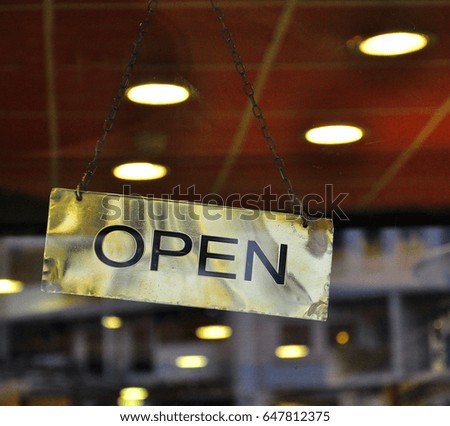 Golden open sign hanging on the door in the street cafe