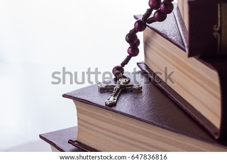Rosary and cross on the Bible on a wooden background. Holy book.