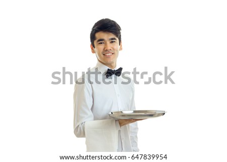 attractive smiling young waiter looks at the camera and holding a tray with a towel