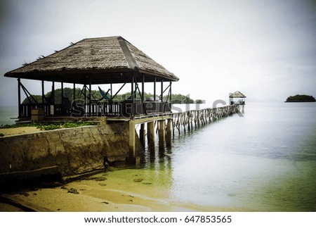 Wooden jetty crossing scenic turquoise see in tourist resort on desert island. Summer adventures on the remote Togian (Togean) Islands, Central Sulawesi, Indonesia.