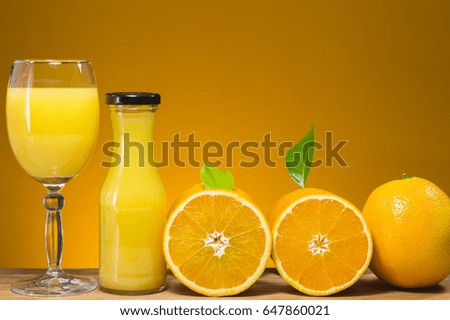 glass jar of fresh orange juice and fresh fruits on orange background