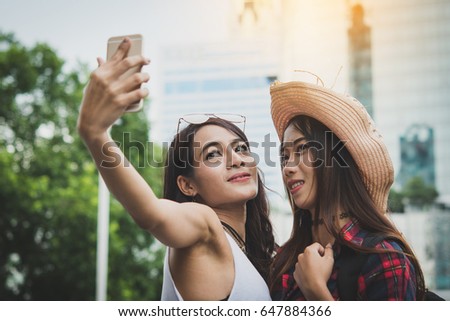 Two young girls on the on the street making selfie with smart phone
