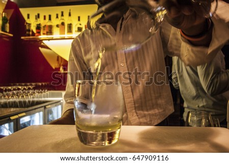 Wine glass with ice cubes on table, inside at a hotel, colorized photograph including perfect lights, very tasty cool drink of luxury restaurant.