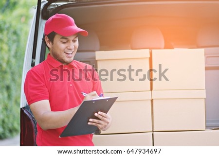 Portrait delivery man of confidence express courier next to his delivery van or Check stock Courier holding carton box and delivery receipt.  asian man