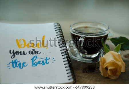 Father's day concept. DAD YOU ARE THE BEST message calligraphy handwriting on white paper notebook with rose and coffee on wooden table top background