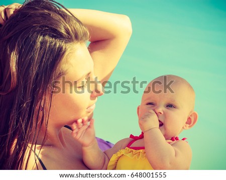 Woman and child posing in swimsuit on sunny day