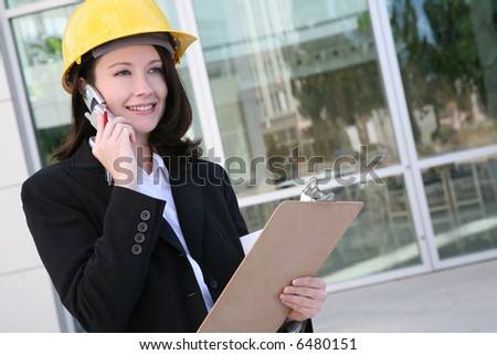 A pretty woman architect holding blueprints and talking on the phone
