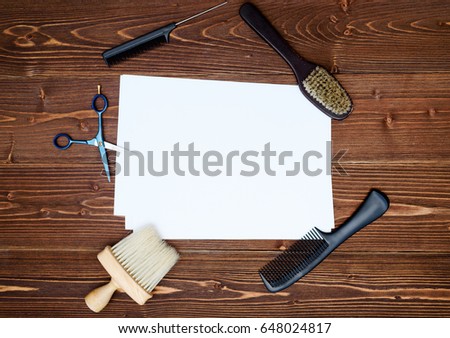 Hairdresser tools on wooden background. Blank card with barber tools flat lay. Top view on wooden table with scissors, comb and brush with empty white paper, free space