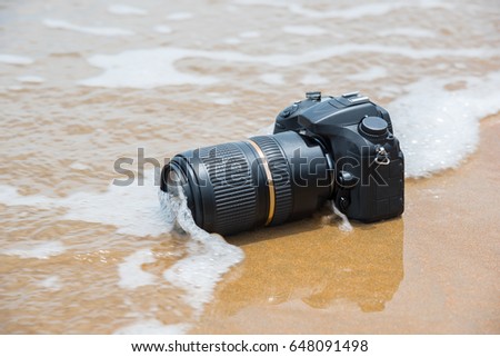 Photographer demo waterproof for DSLR camera and tele lens by wet from water sea wave at beach when travel and test using in the extreme environment