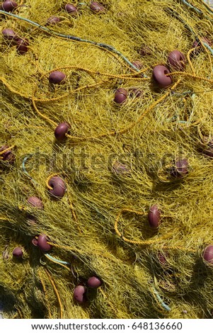 Yellow fishing net left on the dock - close up detail, background, vertical image. Kassiopi Port, Corfu Island, Greece