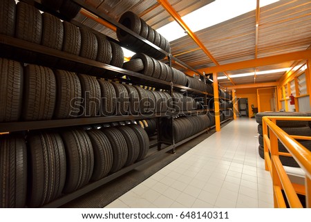 Large modern warehouse with forklifts and stack of car tires