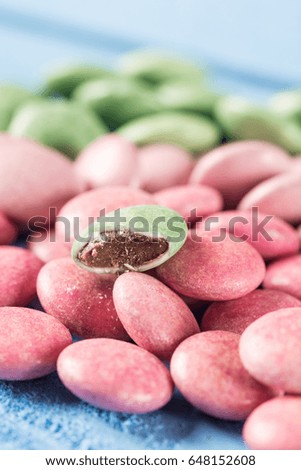 Red and green round chocolate candies on the blue wooden table.