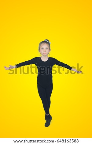Wonderful little child ballerina posing on yellow background