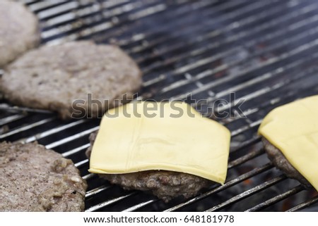 Hamburger Patties on Barbecue with cheese.