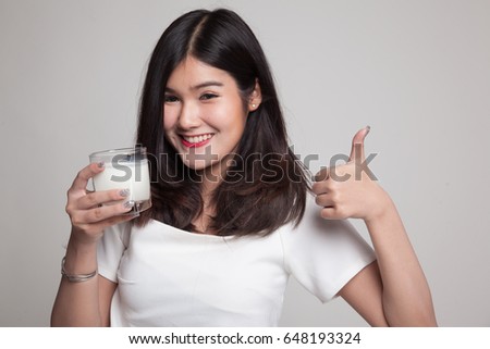 Healthy Asian woman drinking a glass of milk thumbs up on gray background