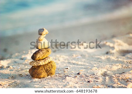 Zen Stones on beach for perfect meditation. Calm zen meditate background with rock pyramid on sand beach symbolizing stability, harmony, balance. Shallow depth of field. Sea pebbles tower closeup.