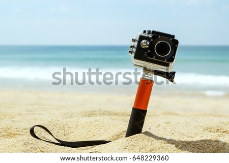 Action camera in waterproof case with monopod on the beach Royalty-Free Stock Photo #648229360