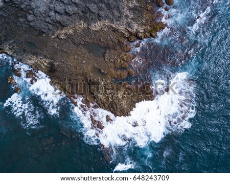 Drone Photography shot above rocky environment with amazing color of the atlantic ocean hitting the granite rocks on the coast somewhere on gran canaria, canary islands, spain. 