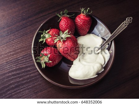 Strawberries with cream on a plate with a spoon