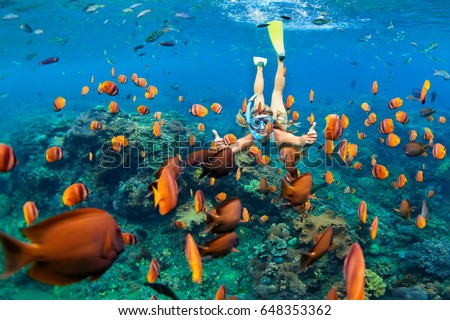 Happy family - girl in snorkeling mask dive underwater with tropical fishes in coral reef sea pool. Travel lifestyle, water sport outdoor adventure, swimming lessons on summer beach holiday with child