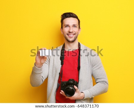 Handsome photographer with business card on color background